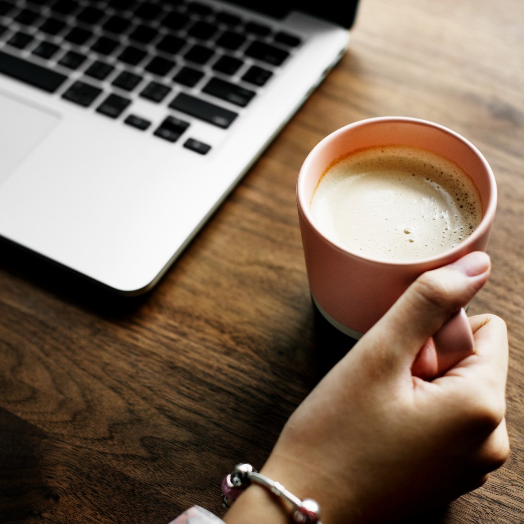 A cup of nice hot coffee next to a computer laptop